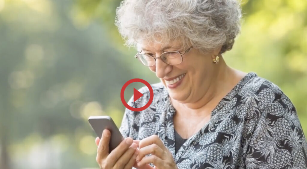 Older woman smiling as she reads the screen on her phone